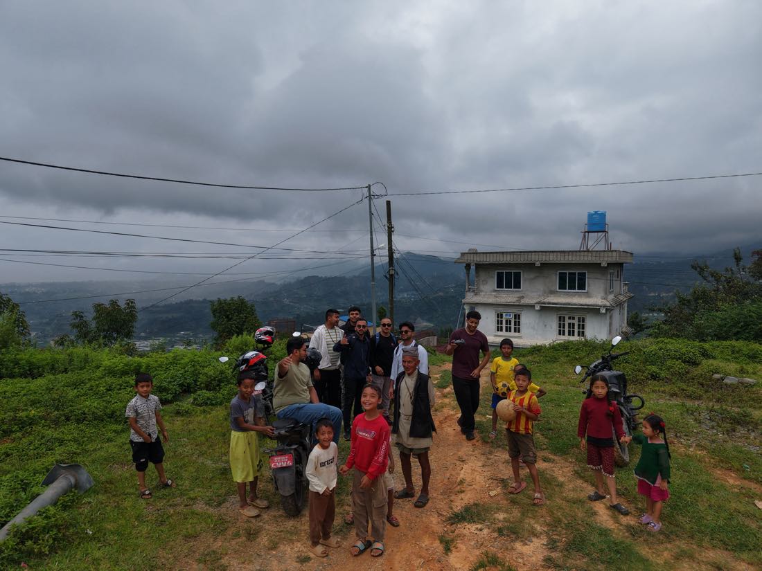 Villagers and children gathered on the track through Chhaimale with Reddy2Help and local partners, the Kathmandu valley behind under heavy cloud.