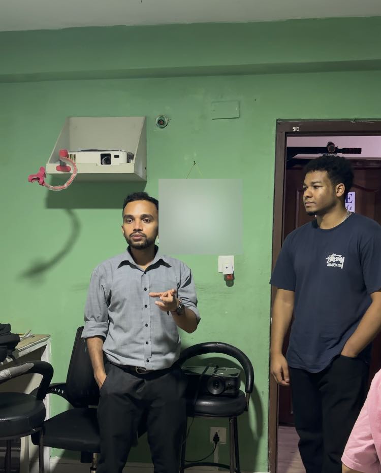 Diwas Rathod speaking to the room at the Asha school, Shawn Reddy standing beside him in a doorway.